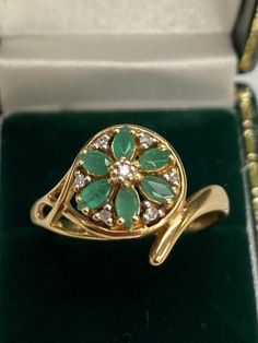 This feminine floral emerald & diamond ring is crafted in the warm hue of 9 carat yellow gold. Ring size: R New Insurance Price: £465.00 Elegant 14k Stamped Emerald Ring, Luxury Yellow Gold Cluster Emerald Ring, Luxury Cluster Emerald Ring In Yellow Gold, Yellow Gold Flower Ring With 17 Jewels For Anniversary, Anniversary Yellow Gold Flower Ring With May Birthstone, Gold Emerald Cluster Ring With Brilliant Cut, Cluster Emerald Ring In Yellow Gold With 17 Jewels, Formal Green Cluster Ring Stamped 14k, Emerald Cluster Ring In Yellow Gold For May Birthstone