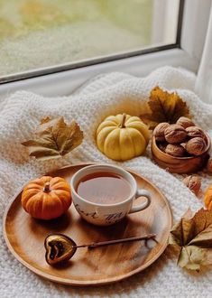 a cup of coffee sits on a plate next to some nuts and leaves, along with other autumn decorations