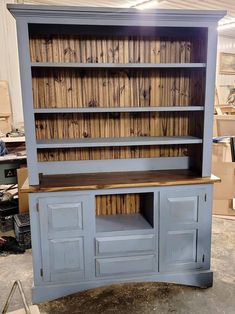 an old blue bookcase with wooden doors and drawers