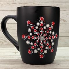 a black coffee mug with red and white designs on the outside, sitting on a wooden table