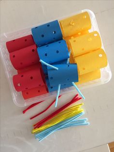 several popsicles are in a plastic container with toothpicks on the top one is yellow, red, and blue