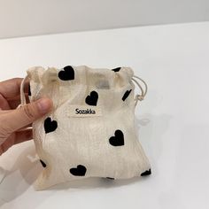 a hand is holding a small pouch with hearts on the front and black dots on the back