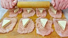 the person is rolling out cheese on top of raw meat and ready to be cut into smaller pieces