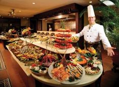 a chef standing in front of a buffet filled with lots of different types of food