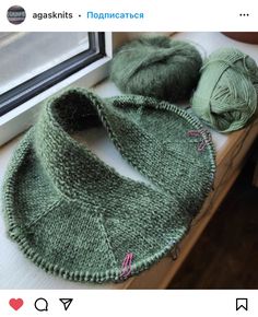 two balls of yarn sitting on top of a table next to a window sill