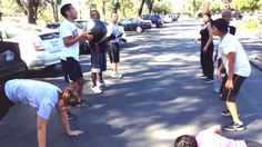 a group of people standing on the side of a road next to cars and trees