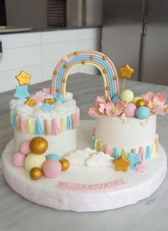 two cakes decorated with rainbows, stars and clouds on top of a white table