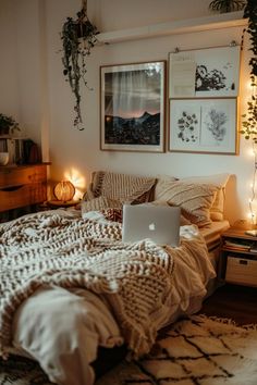 a laptop computer sitting on top of a bed next to a lamp and potted plant