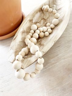 a wooden beaded necklace on a plate next to a potted plant