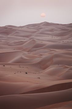 the sun is setting over sand dunes in the desert