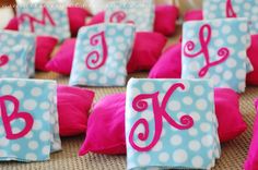 pink and blue polka dot pillows with the letter j on them are sitting on a table