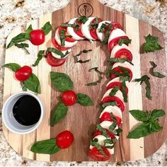 a wooden cutting board topped with sliced tomatoes and veggies