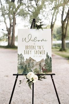 a welcome sign for an outdoor wedding with white flowers and greenery on the top