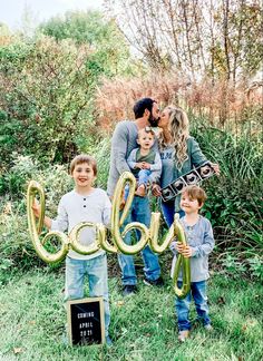 a family posing for a photo with the word joy spelled out in large letters and balloons