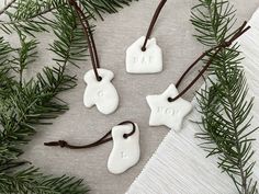 three white ceramic ornaments with the words i love you hanging from brown cord on a table