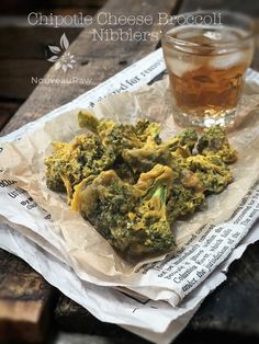 a plate with broccoli on it next to a glass of tea and napkins