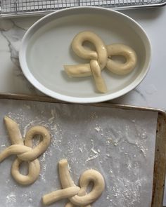 some pretzels are sitting on a baking sheet next to a bowl and pan