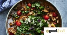 a bowl filled with meat and vegetables on top of a blue table cloth next to a napkin