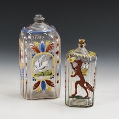 two glass bottles with designs on them sitting next to each other