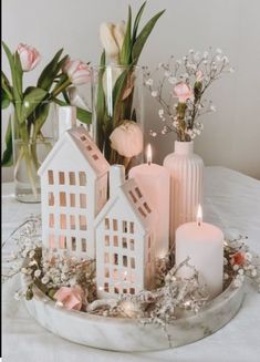 a tray with candles, flowers and houses on it