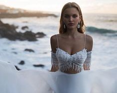 a woman in a white dress standing by the ocean