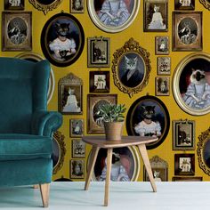 a blue chair sitting in front of a yellow wall with pictures and cats on it