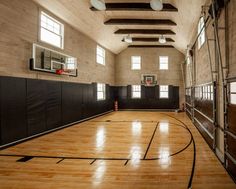 an indoor basketball court with hard wood flooring and ladders leading up to the ceiling