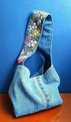 a purse made out of old jeans is sitting on a table next to a blue wall