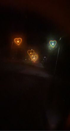 some lights are shining in the dark with hearts on them and one light is green