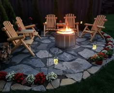 a fire pit surrounded by lawn chairs and flowers in the evening time with lit candles