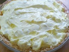 a pie with white frosting sitting on top of a wooden table