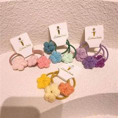 several small crocheted flowers are on display in front of the name tag and price tags