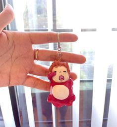 a hand is holding a small keychain with a little red haired girl on it