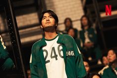 a man standing in front of a crowd wearing a green and white shirt with numbers on it