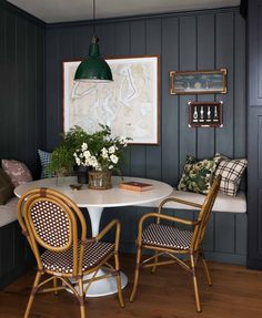 a dining room table with chairs and a map on the wall above it, next to a bench