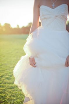 a woman in a white dress walking across a field