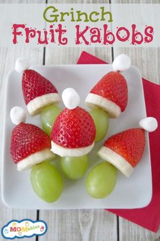 some grapes and strawberries are arranged in santa hats on a white plate with green grapes