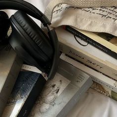 headphones and books on a bed with white sheets