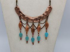 "This unique handmade statement necklace features a curved copper finish hammered bar component accented by drops created with ornate vintage copper beads, faceted copper/pink/gold crystal rondells and ending with textured turquoise magnesite stone leaves. The whole design is brought together with a subtle backdrop of copper link chain \"netting\" and is finished with custom copper lantern chains and a lobster clasp closure. This extraodinary piece comes complete with matching earrings, which me Bohemian Jewelry In Copper Wire With Patina, Unique Copper Jewelry With Dangling Beads, Bronze Copper Jewelry With Dangling Beads, Bohemian Copper Necklace With Patina, Copper Jewelry With Dangling Beads, Textured Turquoise, Diy Statement Necklace, Handmade Statement Necklace, Copper Lantern