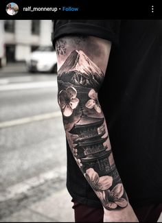 a man with a tattoo on his arm is standing next to the street and has flowers in front of him