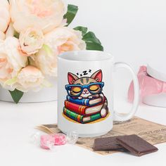 a white coffee mug with a cat wearing glasses and reading books on top of it