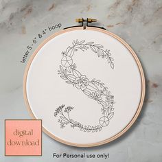 a cross stitch pattern with the letter s on it and an embroidery hoop in front of it