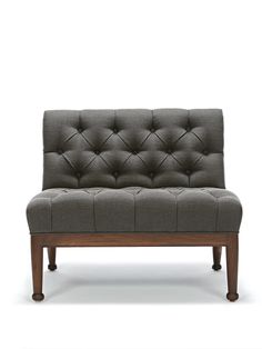 an upholstered couch with wooden legs and buttons on the back, against a white background