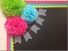 tissue pom poms and streamers on a bulletin board