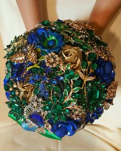 a close up of a person's hand holding a blue and green brooch bouquet