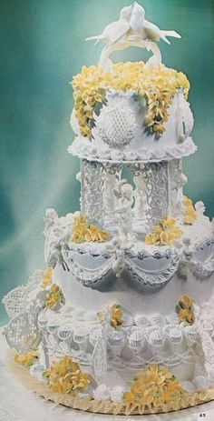 a three tiered wedding cake with yellow flowers on the bottom and white icing