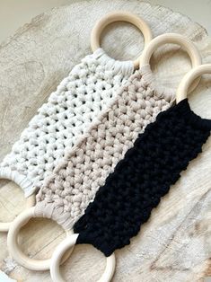 three crocheted objects are sitting on top of a piece of wood, one is black and the other is white