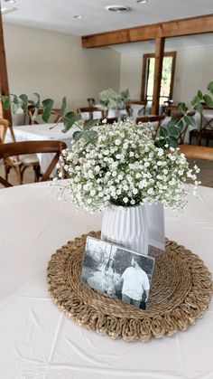 a vase filled with baby's breath sitting on top of a white table cloth