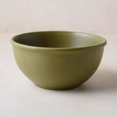 a green bowl sitting on top of a white table