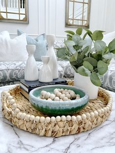 a living room with white couches and green plants on the coffee table in front of it